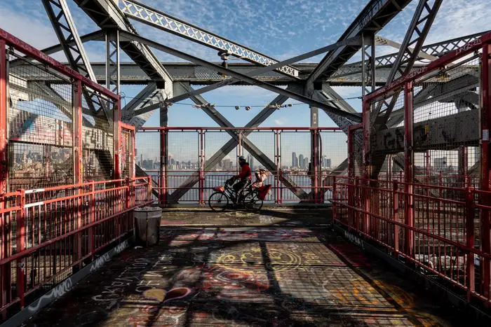 a photo of a father and son biking across the williamsburg bridge